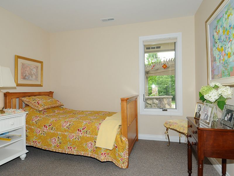 Bedroom with yellow floral quilt, wooden bed, nightstand, and window.