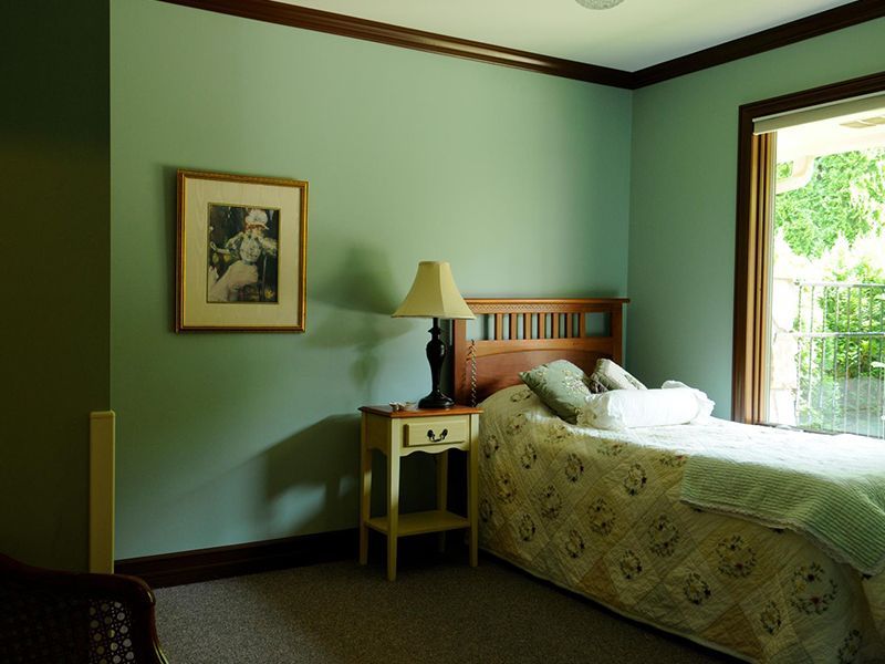 Bedroom with a bed, nightstand, framed artwork, and window, all painted in shades of green.