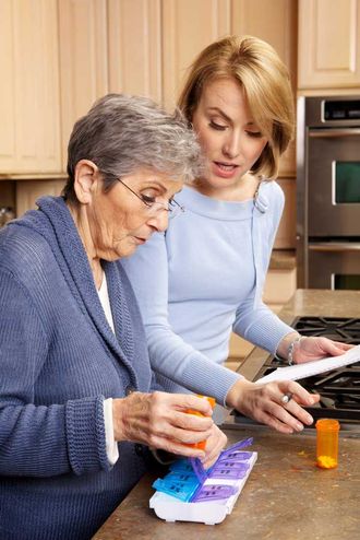 Caregiver helping elderly person with medicine