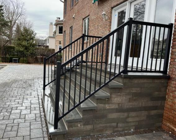 A black railing on a set of stairs leading up to a house.