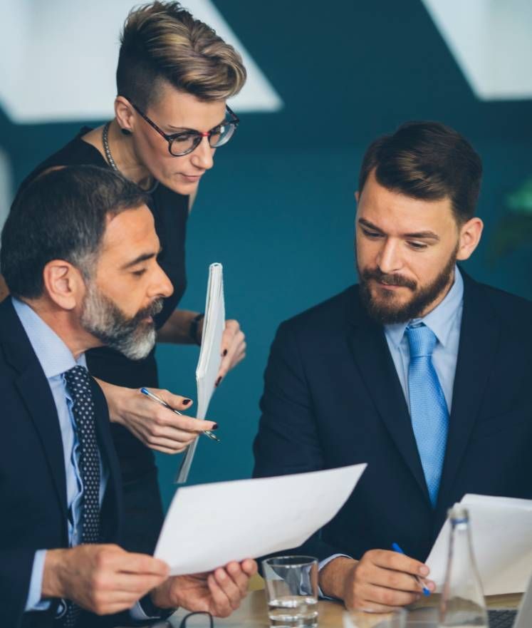 A group of business people are sitting at a table looking at papers.