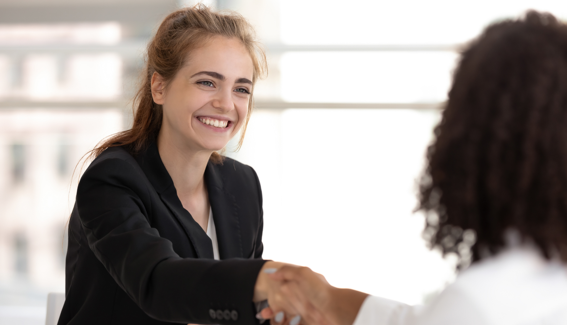 A woman is shaking hands with another woman during a job interview.