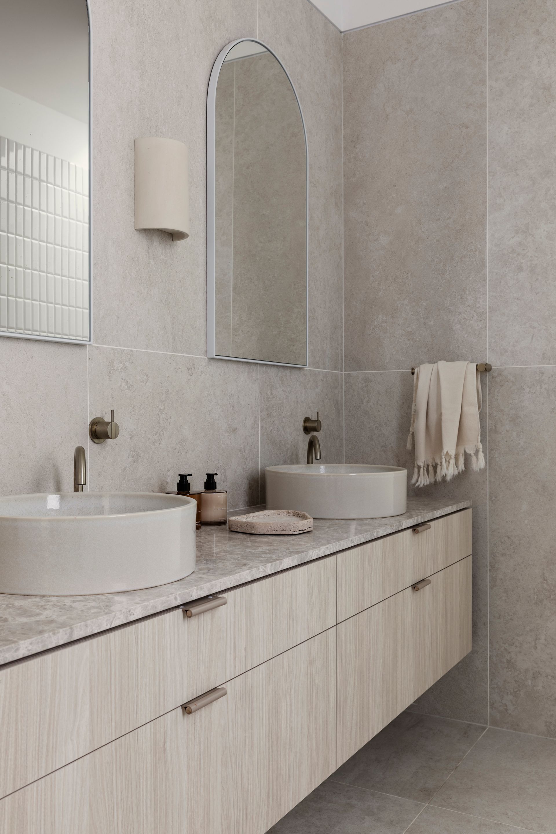 Modern bathroom with dual sinks, arched mirror, neutral colors, and floating vanity — Escarpment Building in Austinmer, NSW