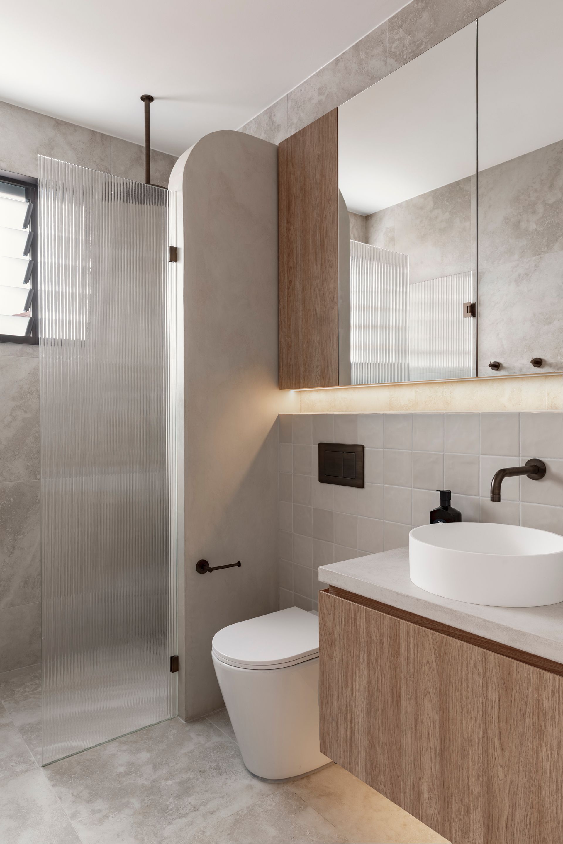 Modern bathroom with neutral tones, shower with fluted glass, wooden vanity, and a round sink — Escarpment Building in Austinmer, NSW