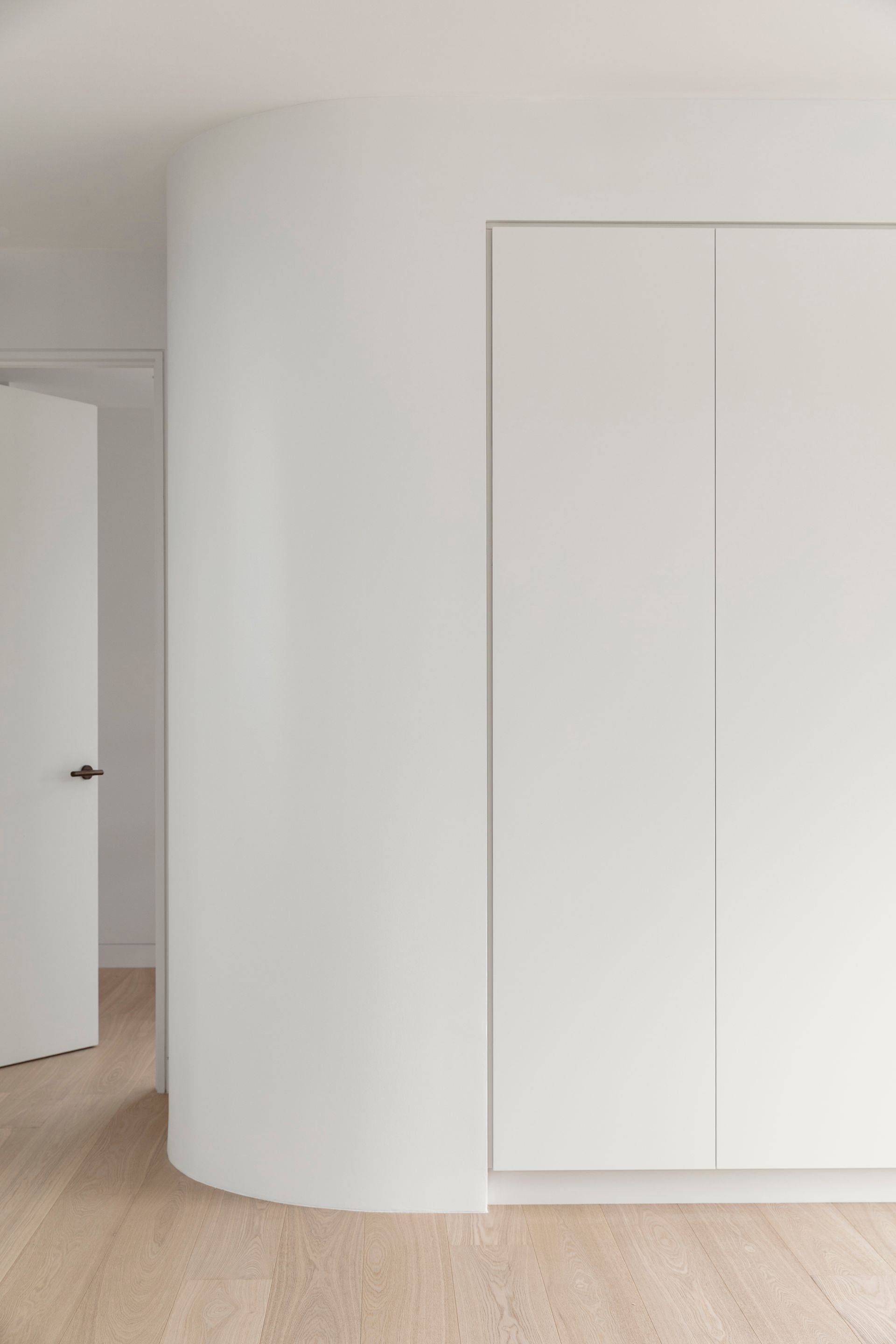 White room interior with curved wall, closet, and open door — Escarpment Building in Austinmer, NSW