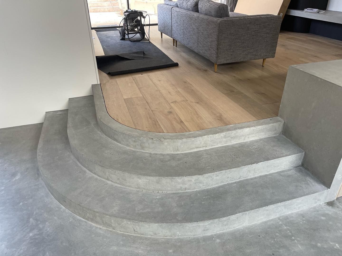 Concrete steps leading up to a wooden floor in a home. Grey steps with rounded edges — Escarpment Building in Austinmer, NSW