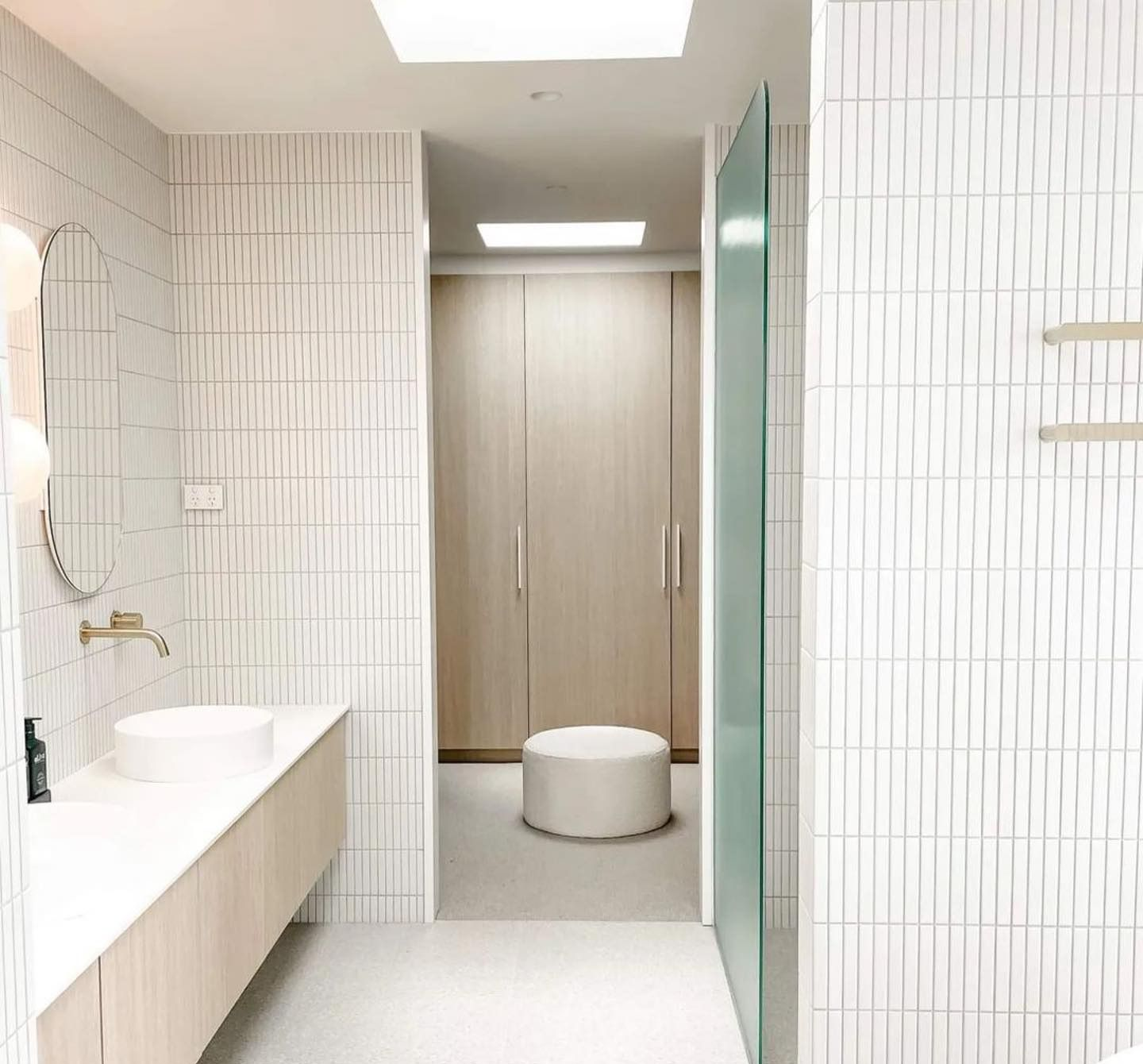 Modern white bathroom with vanity, closet, and vertical tile walls — Escarpment Building in Austinmer, NSW