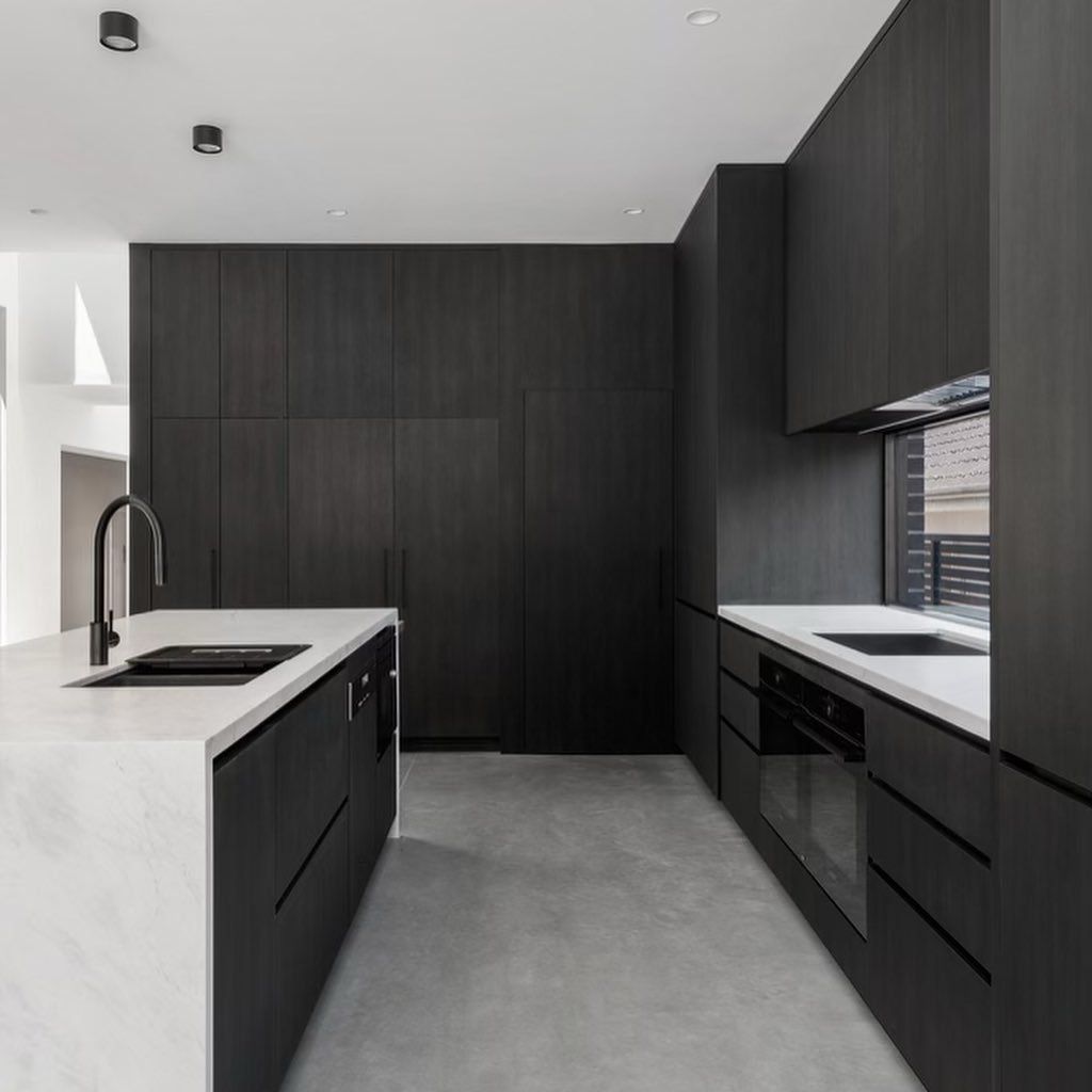 Modern kitchen with black cabinetry, white countertops, and concrete floor — Escarpment Building in Austinmer, NSW