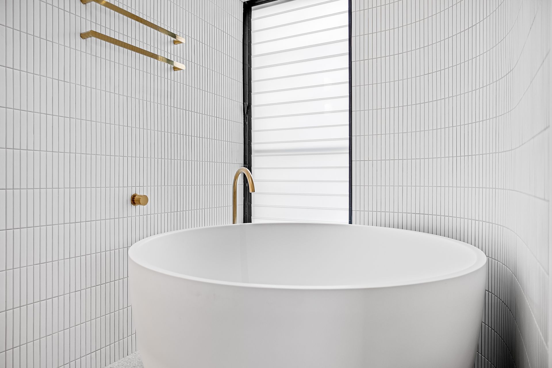 Modern white bathroom with a round tub and vertical tiled walls — Escarpment Building in Austinmer, NSW