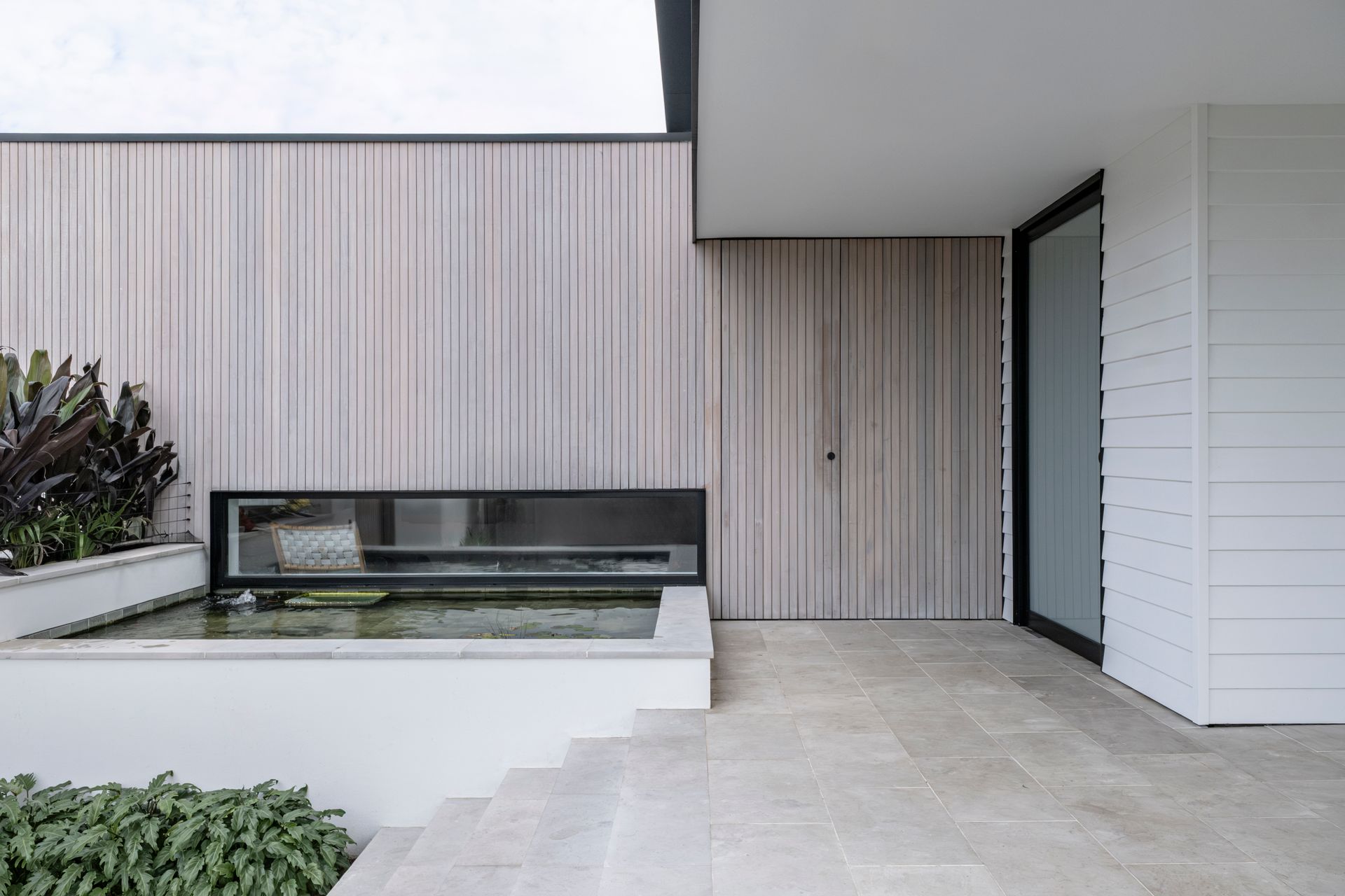 Exterior of a modern home with wood paneling, a reflecting pool, and a doorway — Escarpment Building in Austinmer, NSW