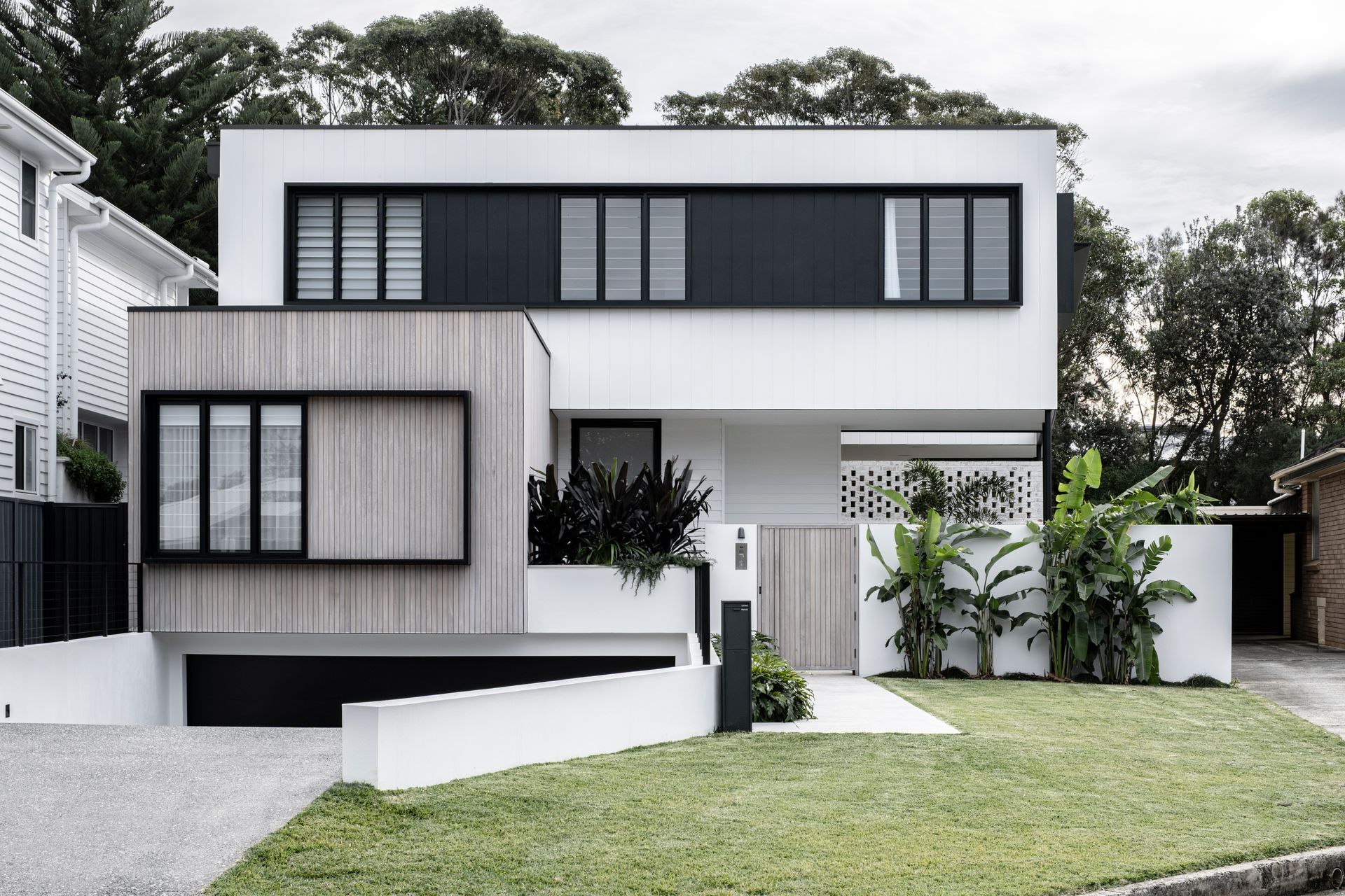 Modern white house with light wood siding and black windows  — Escarpment Building in Austinmer, NSW
