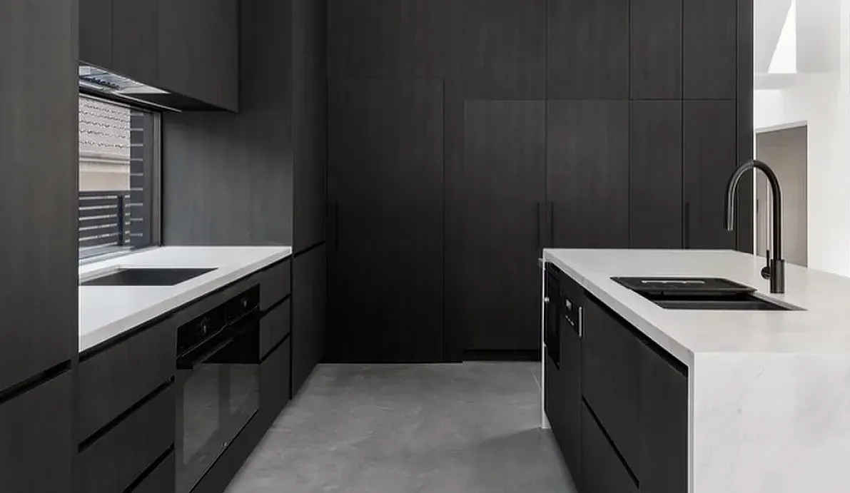 Modern kitchen with dark cabinetry, white countertops, and black faucet— Escarpment Building in Austinmer, NSW