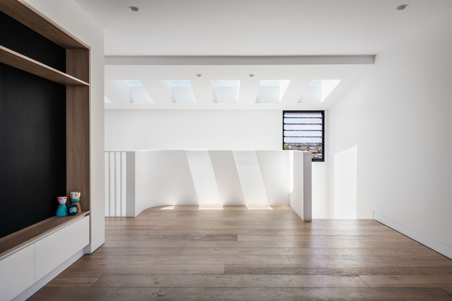 Bright white interior with wood flooring, sunlight, and a built-in shelf with a chalkboard — Escarpment Building in Austinmer, NSW