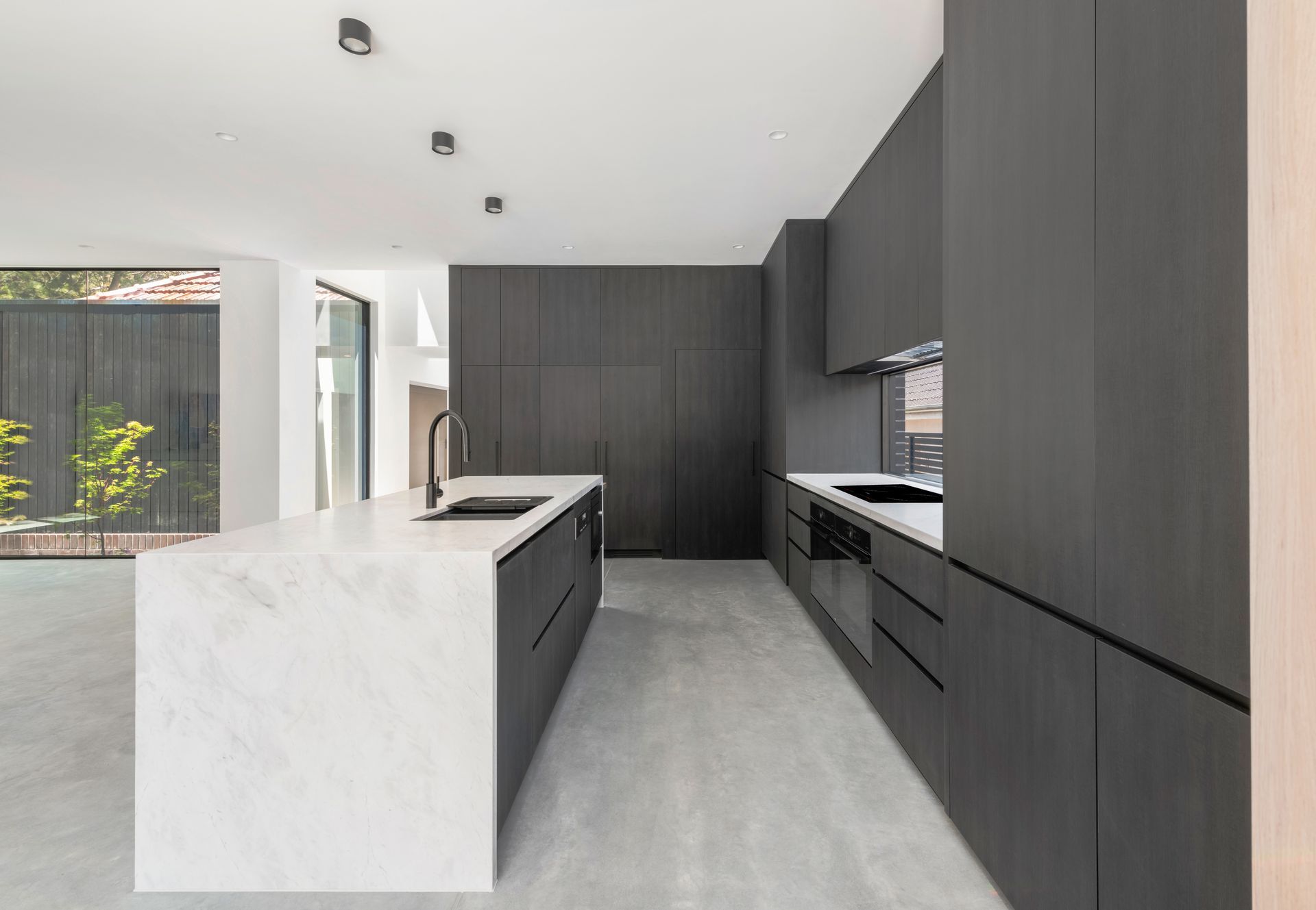 Modern kitchen with dark gray cabinetry, white countertops, and an island — Escarpment Building in Austinmer, NSW