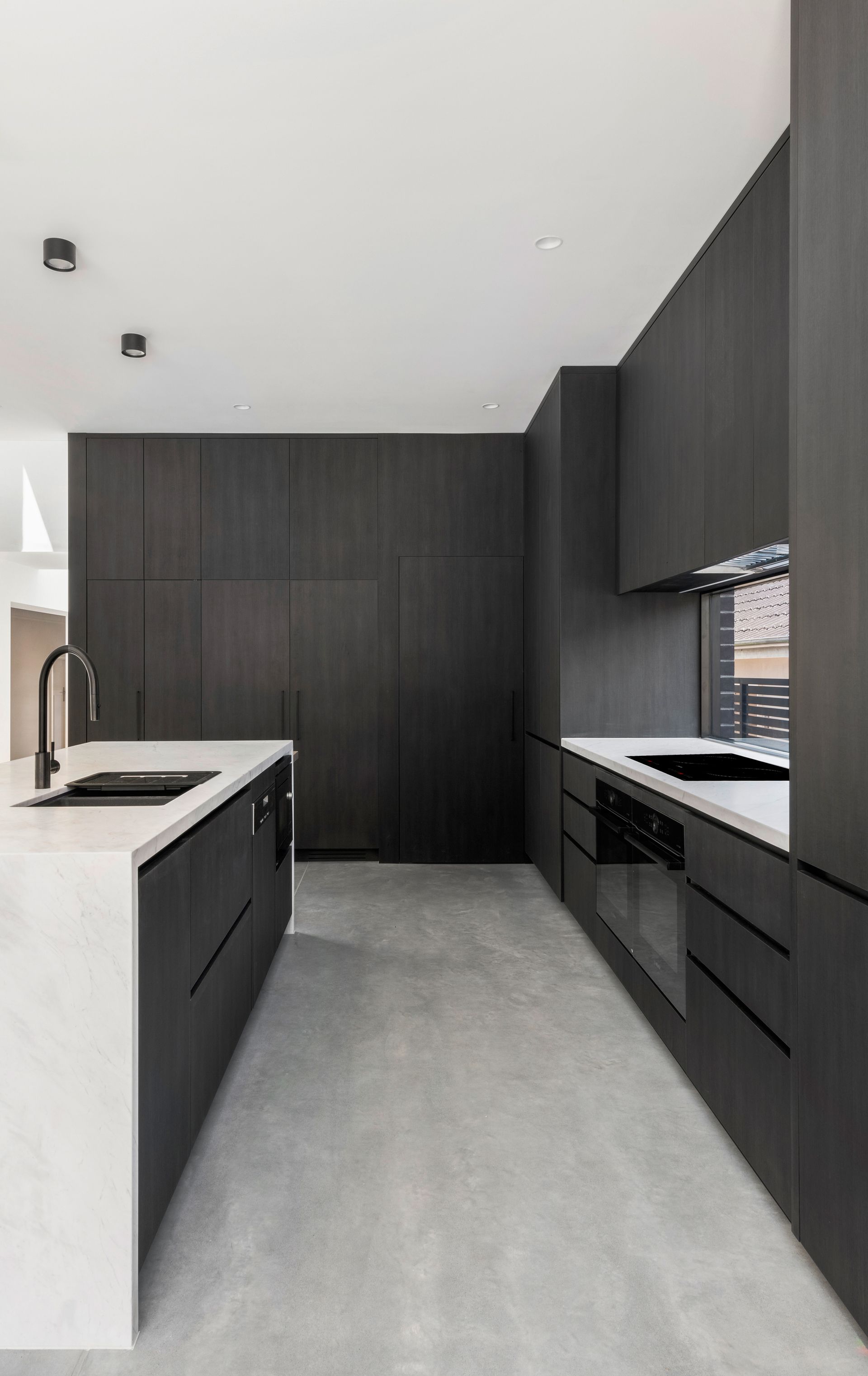 Modern kitchen with dark wood cabinetry, white countertops, and gray flooring — Escarpment Building in Austinmer, NSW