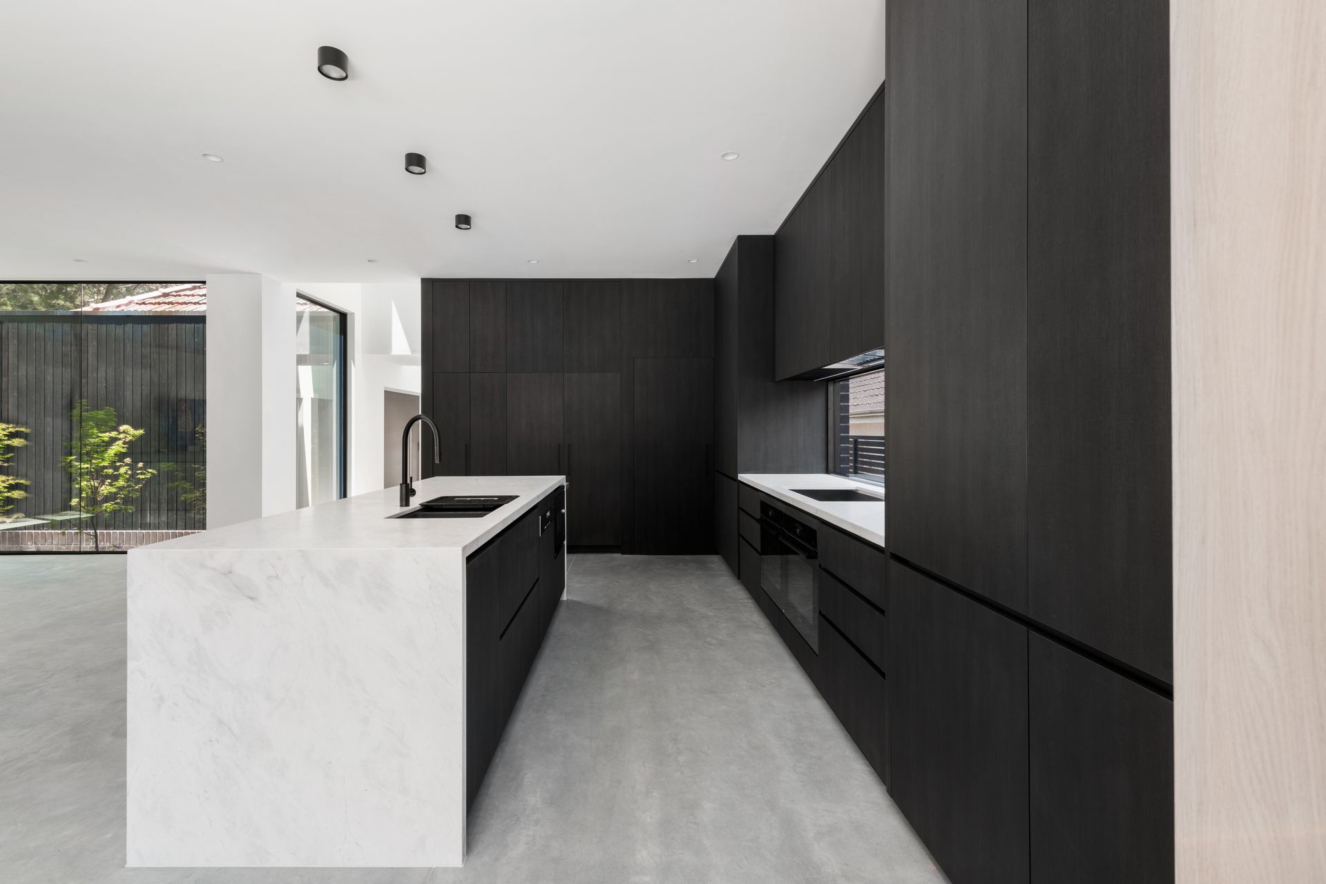 Modern kitchen with black cabinetry, white countertops, and a marble island — Escarpment Building in Austinmer, NSW