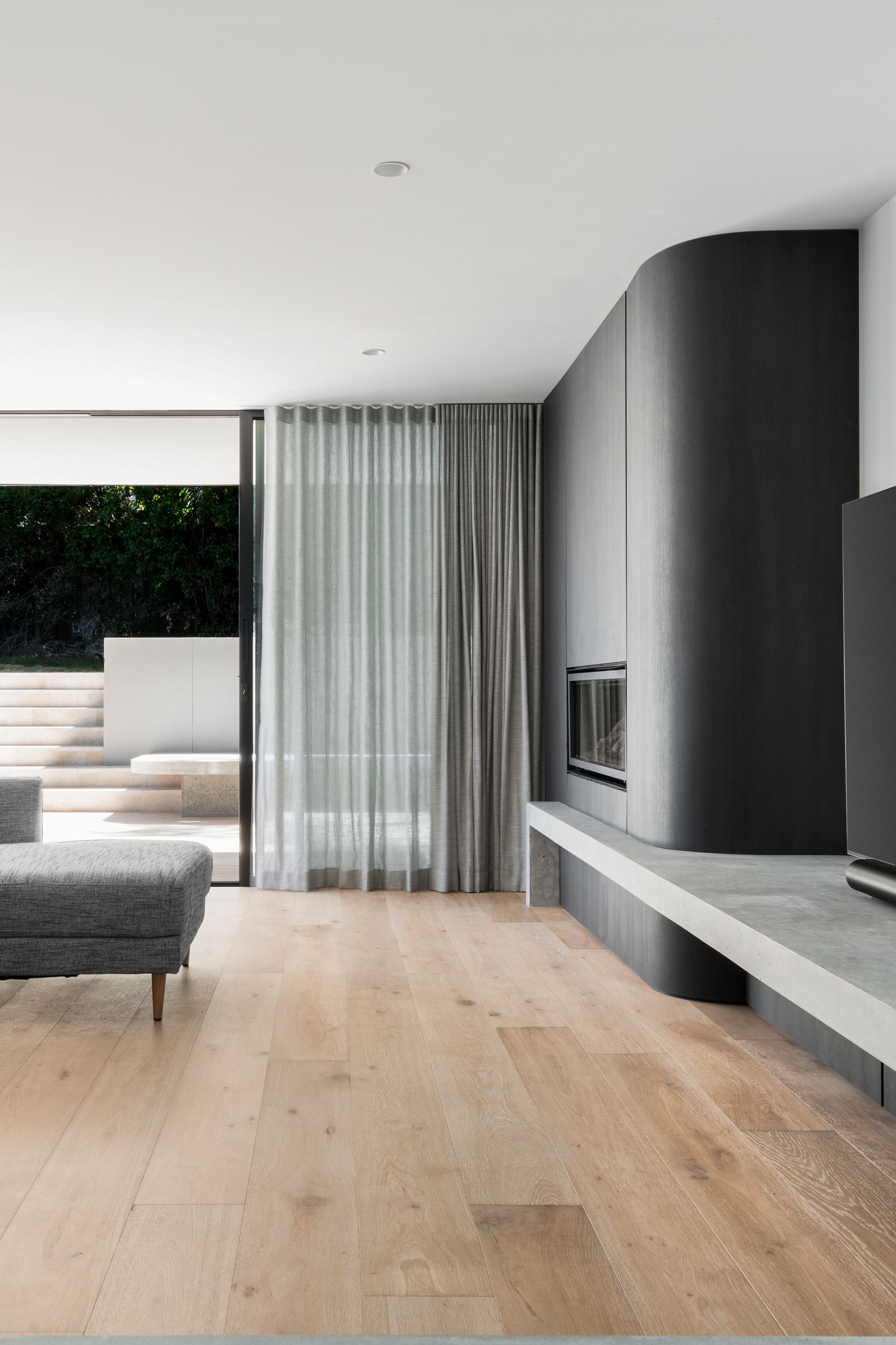 Modern living room with fireplace, sheer curtains, light wood floor — Escarpment Building in Austinmer, NSW