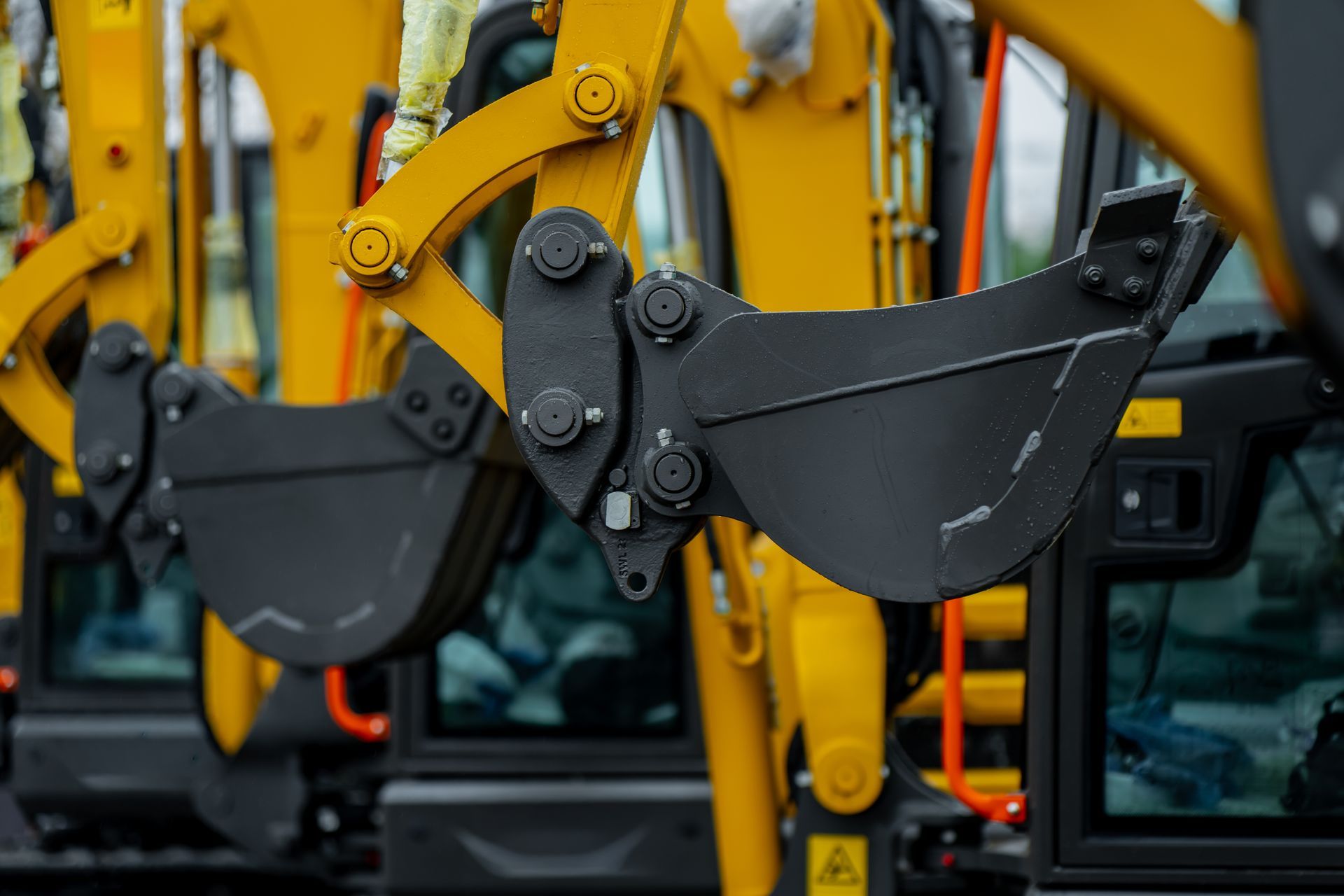 Yellow excavator arms with black buckets on a construction vehicle display lot