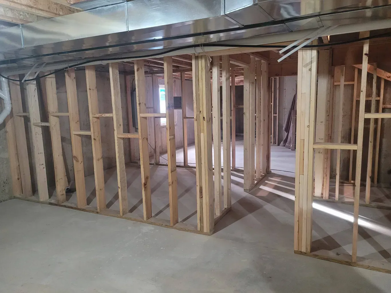 Unfinished basement construction showing newly framed wooden interior walls on a concrete floor.