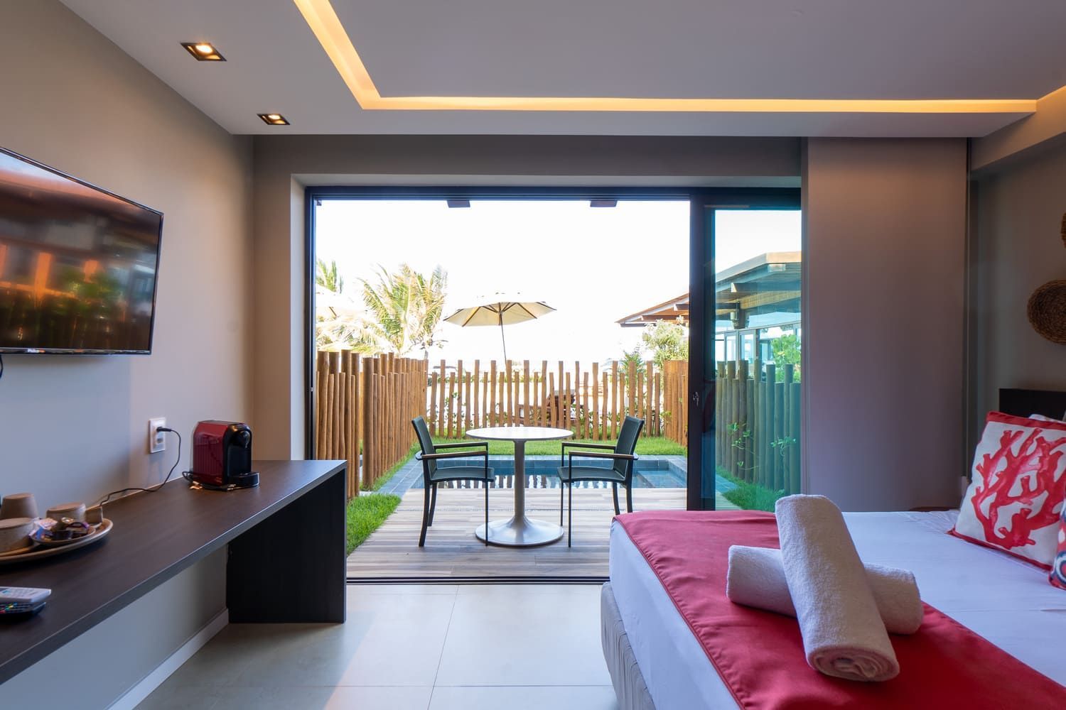 Um quarto de hotel com uma cama, televisão, mesa e cadeiras.