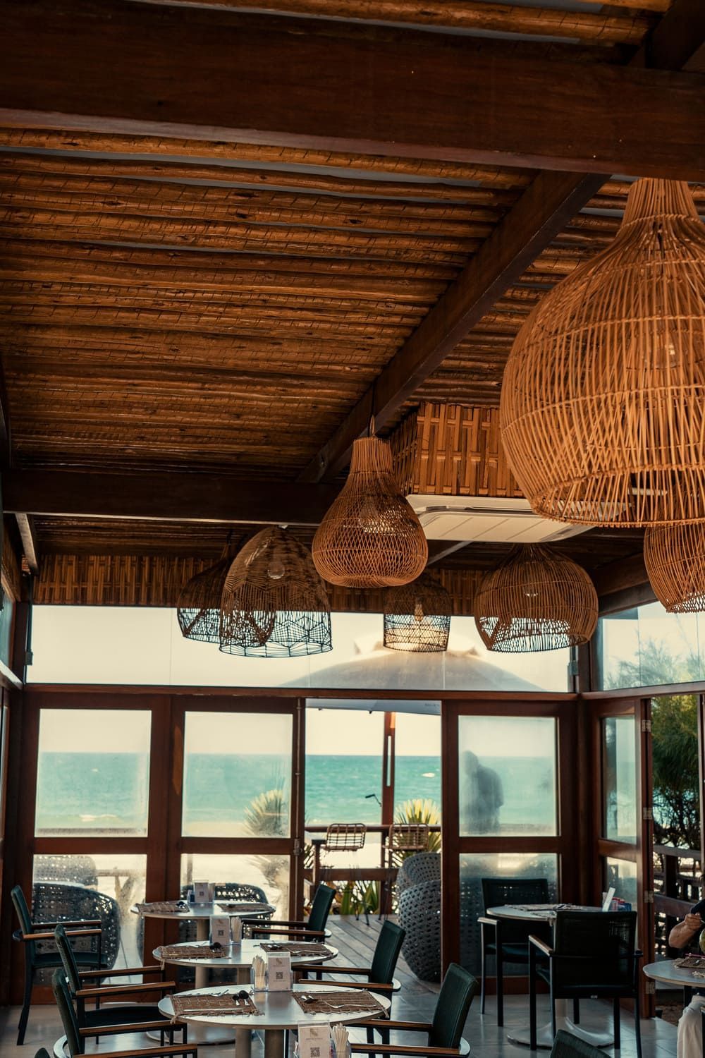 Um restaurante com mesas e cadeiras e vista para o oceano.