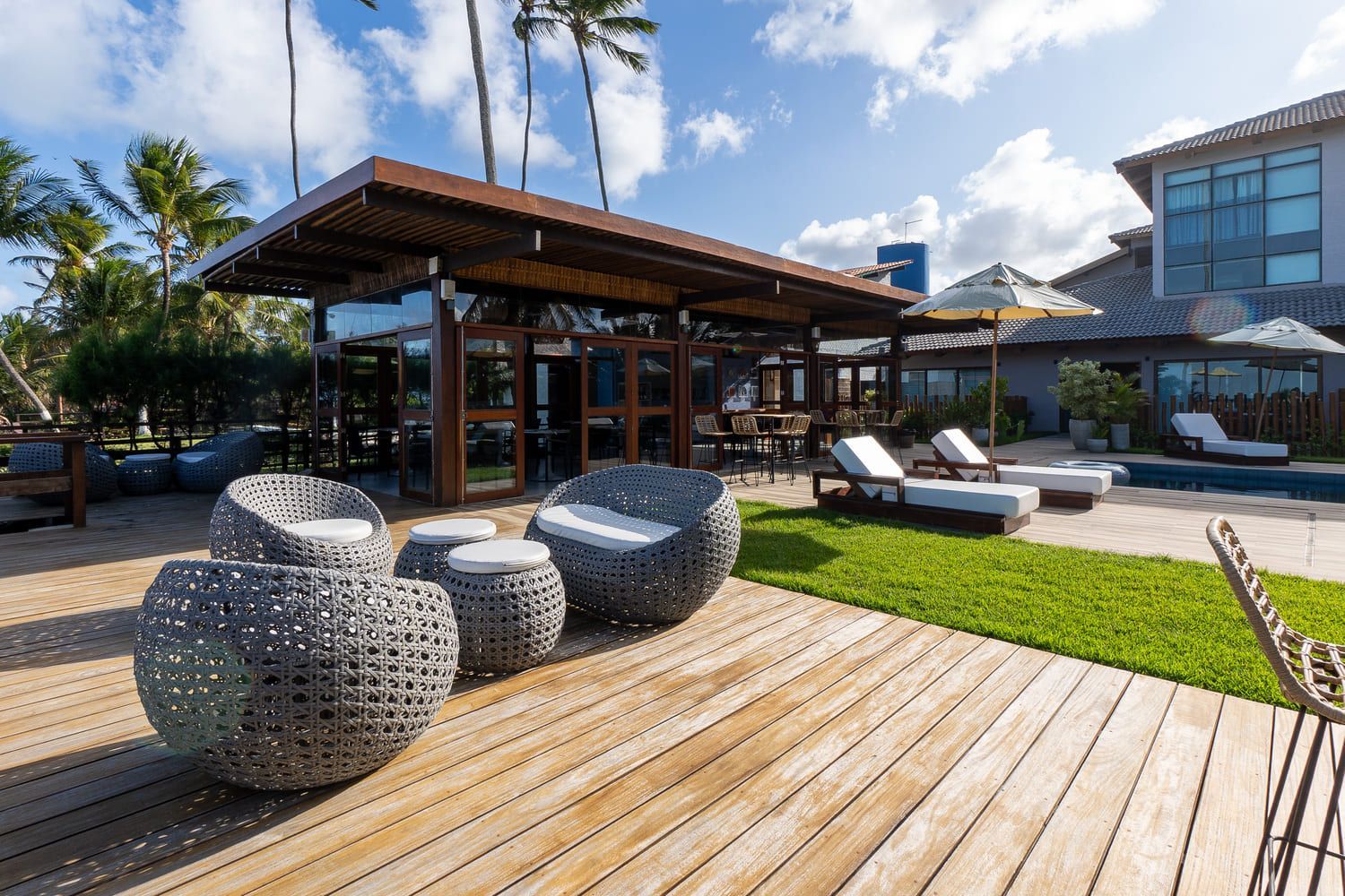 Um deck de madeira com cadeiras e mesas em frente a uma casa.