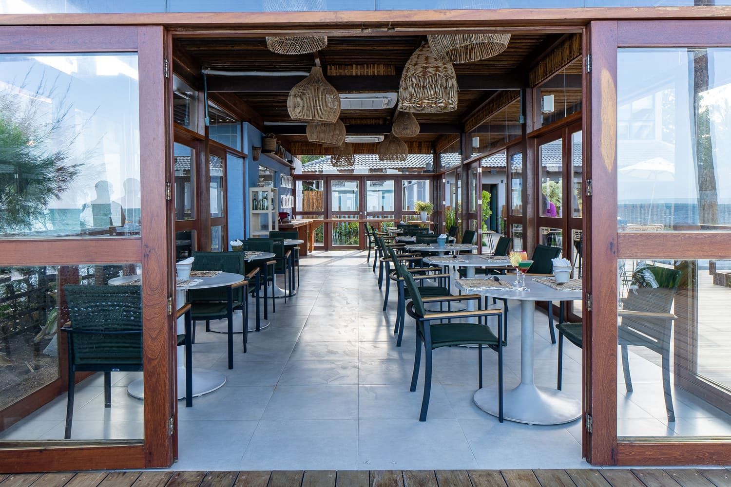 Um restaurante com mesas e cadeiras e vista para o oceano.