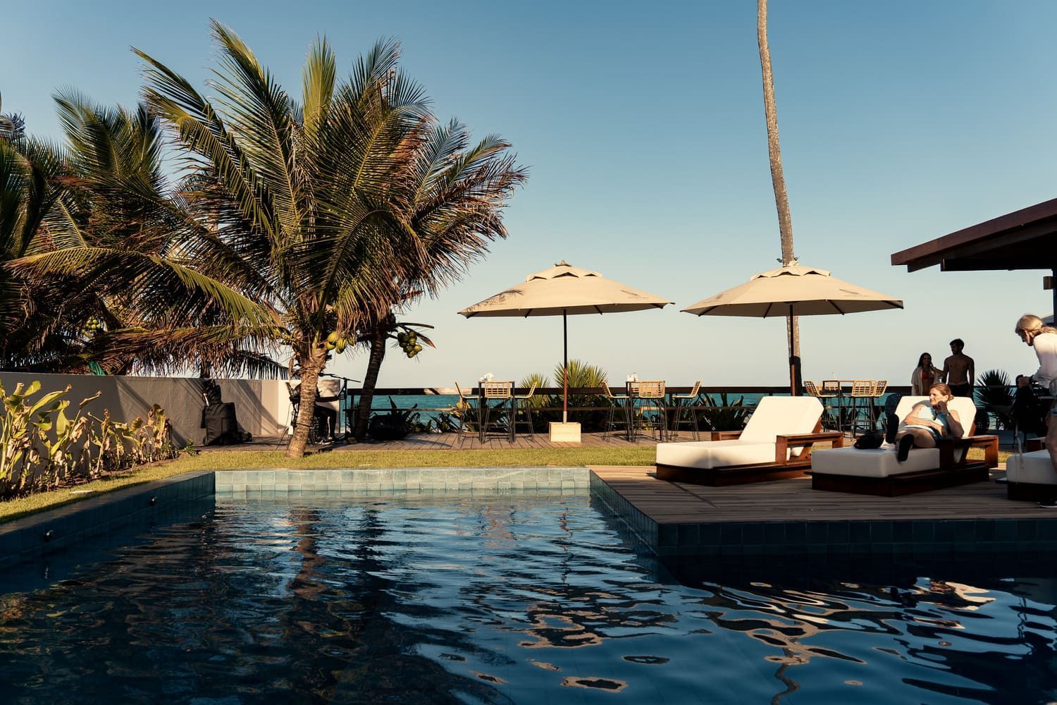 Uma piscina com cadeiras e guarda-sóis ao fundo
