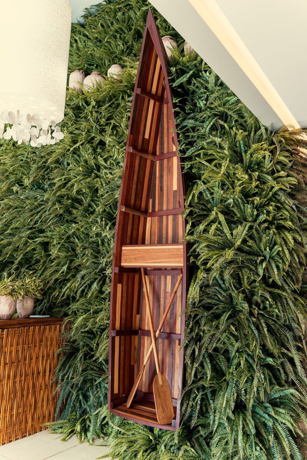 Um barco de madeira com remos está pendurado na parede.