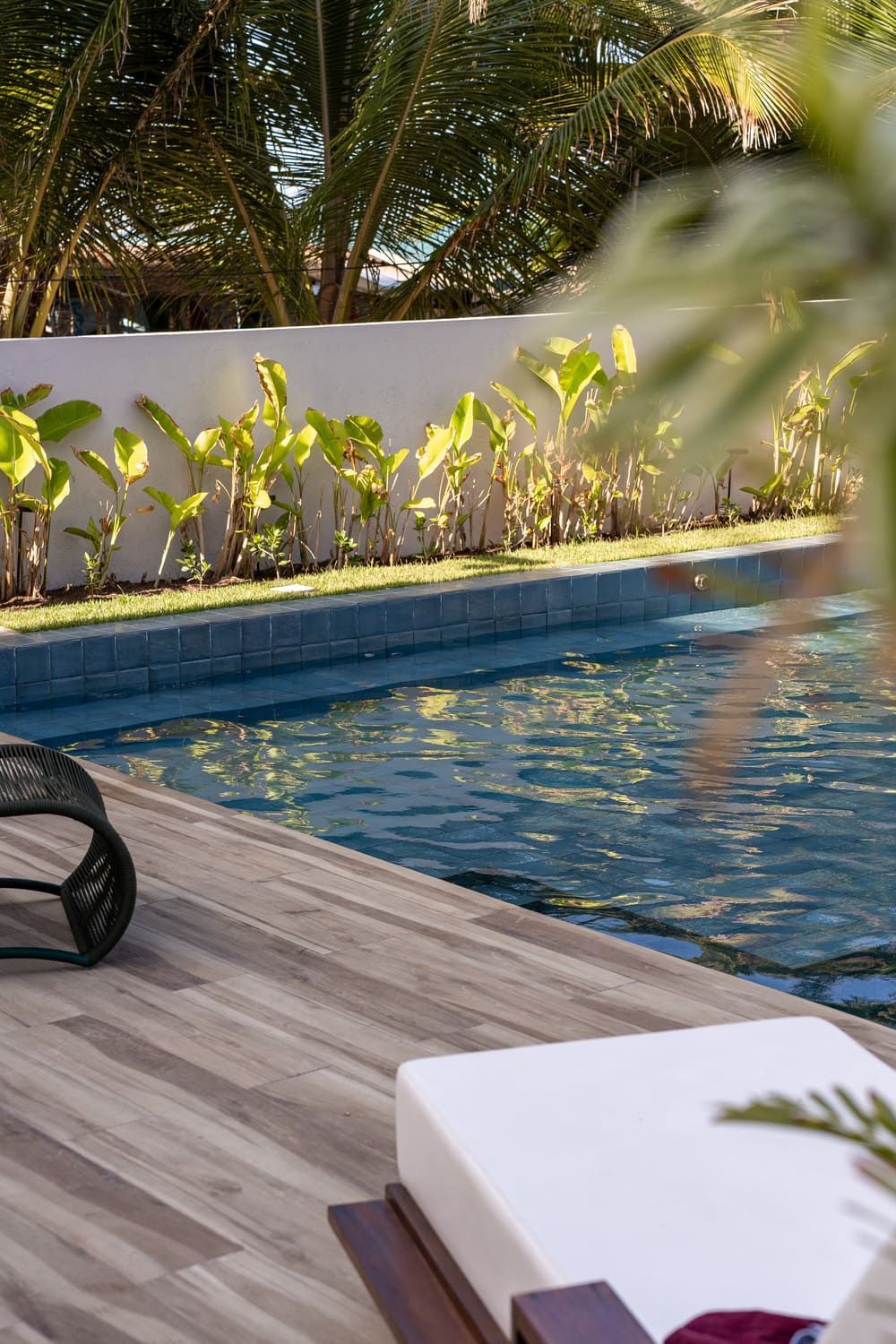 Uma piscina com deck de madeira e cadeiras ao redor.