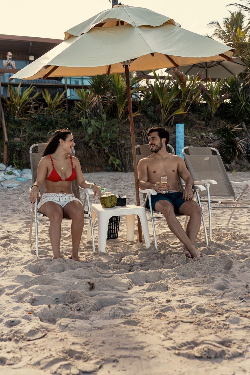 Um homem e uma mulher estão sentados sob um guarda-sol na praia.