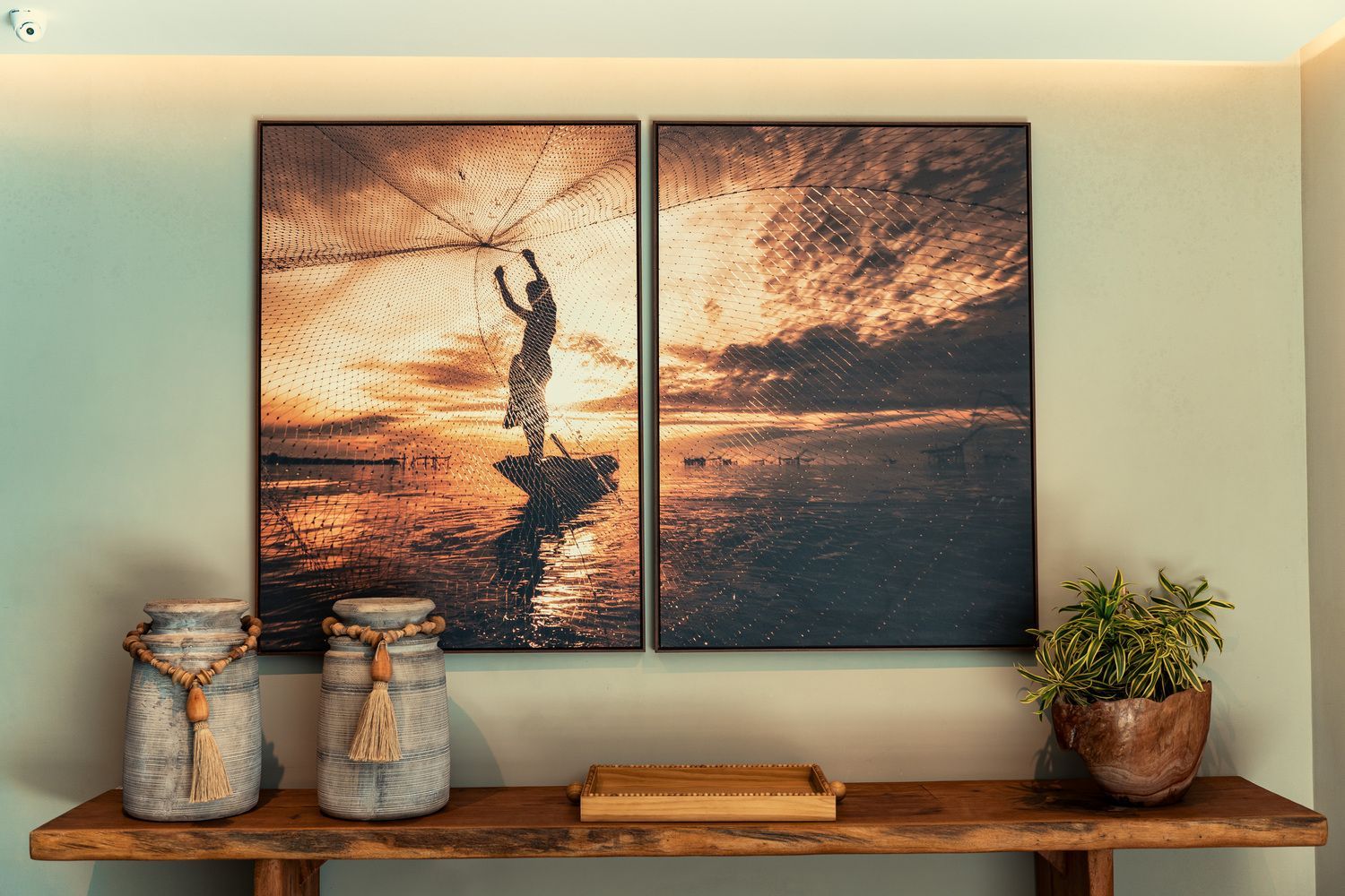 Duas pinturas estão penduradas na parede acima de uma mesa de madeira.