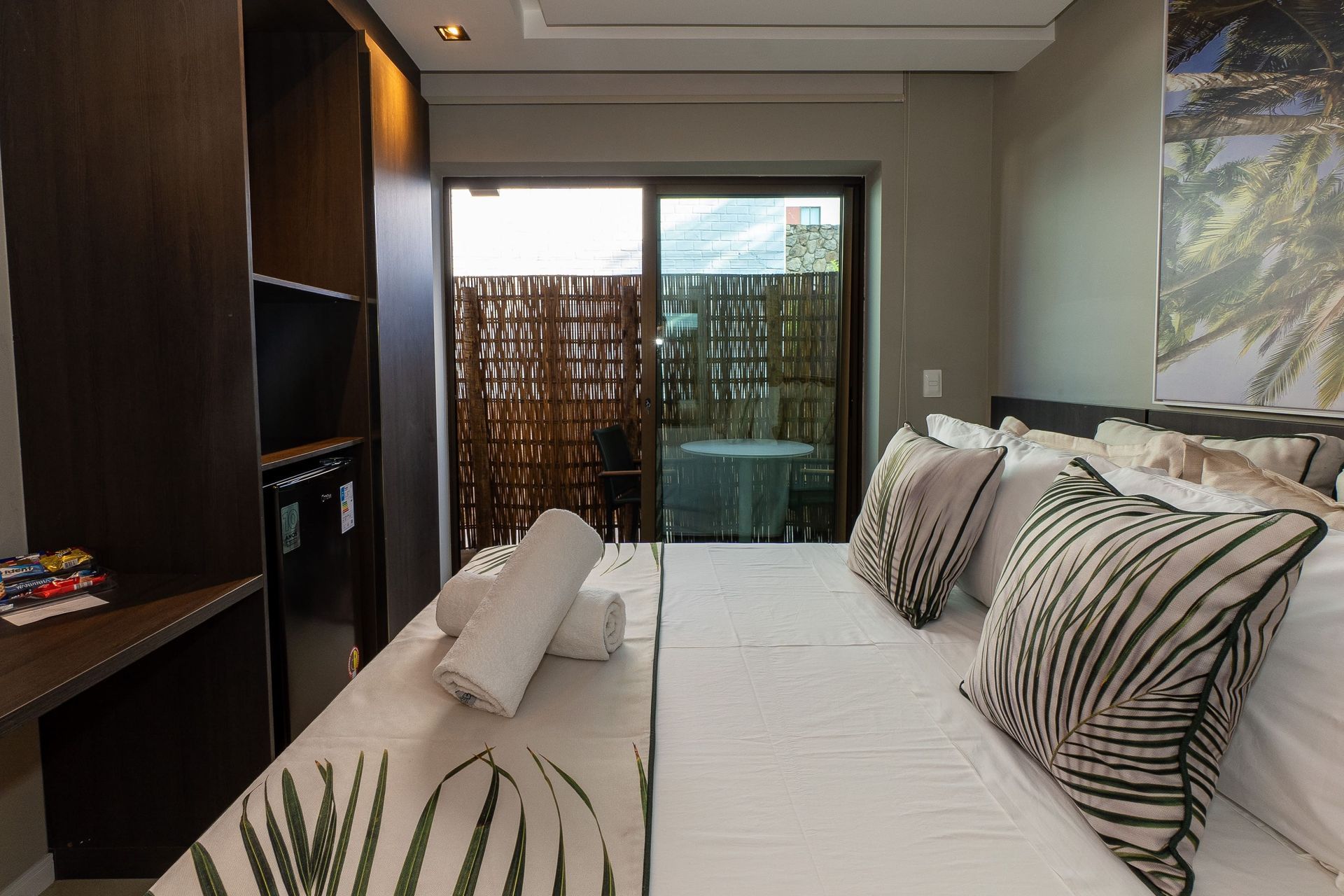 Um quarto de hotel com uma cama grande e uma porta de vidro deslizante que leva a uma varanda.