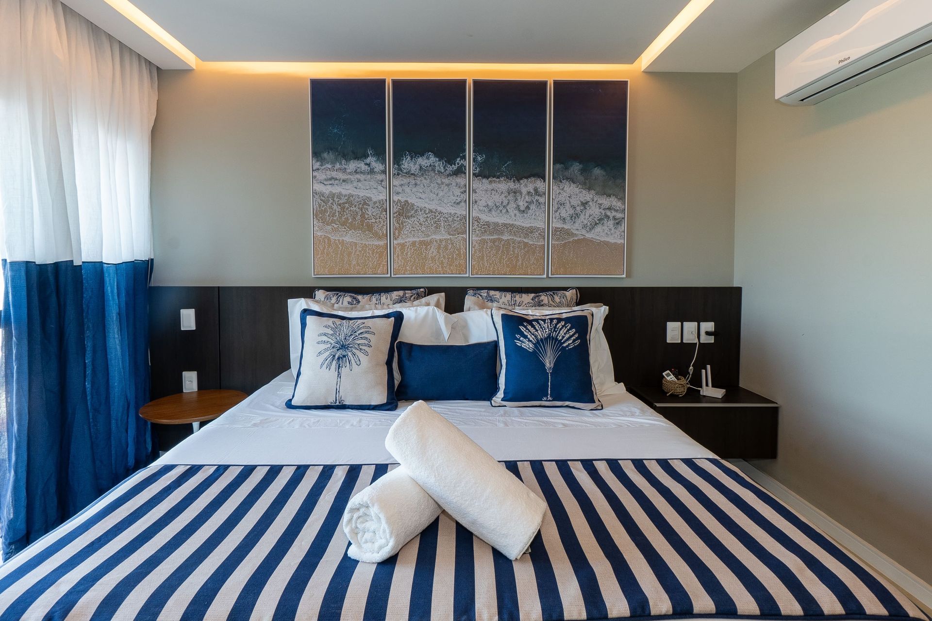 Um quarto com uma cama, mesa de cabeceira e pinturas na parede.