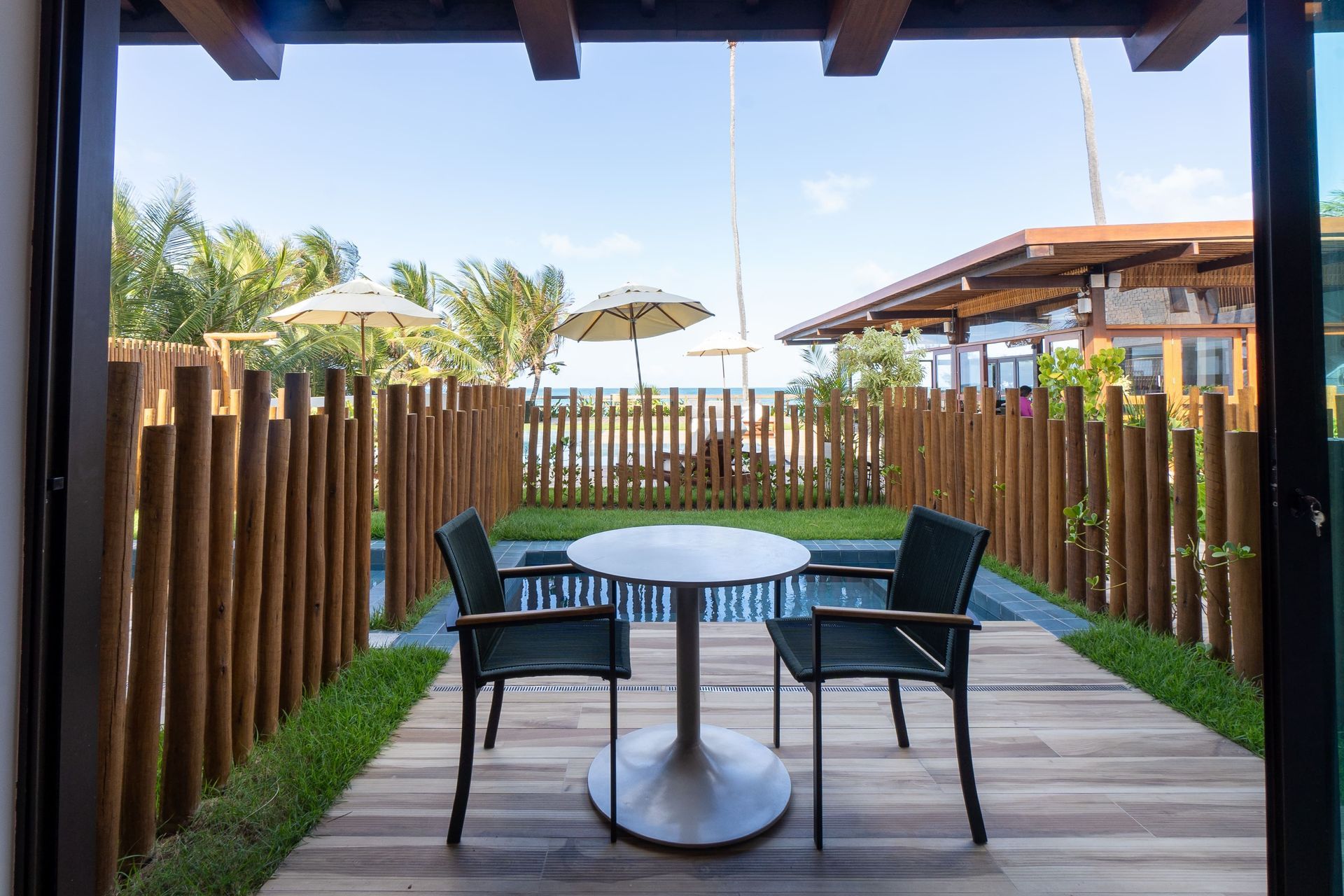 Um pátio com mesa e cadeiras ao lado de uma piscina.