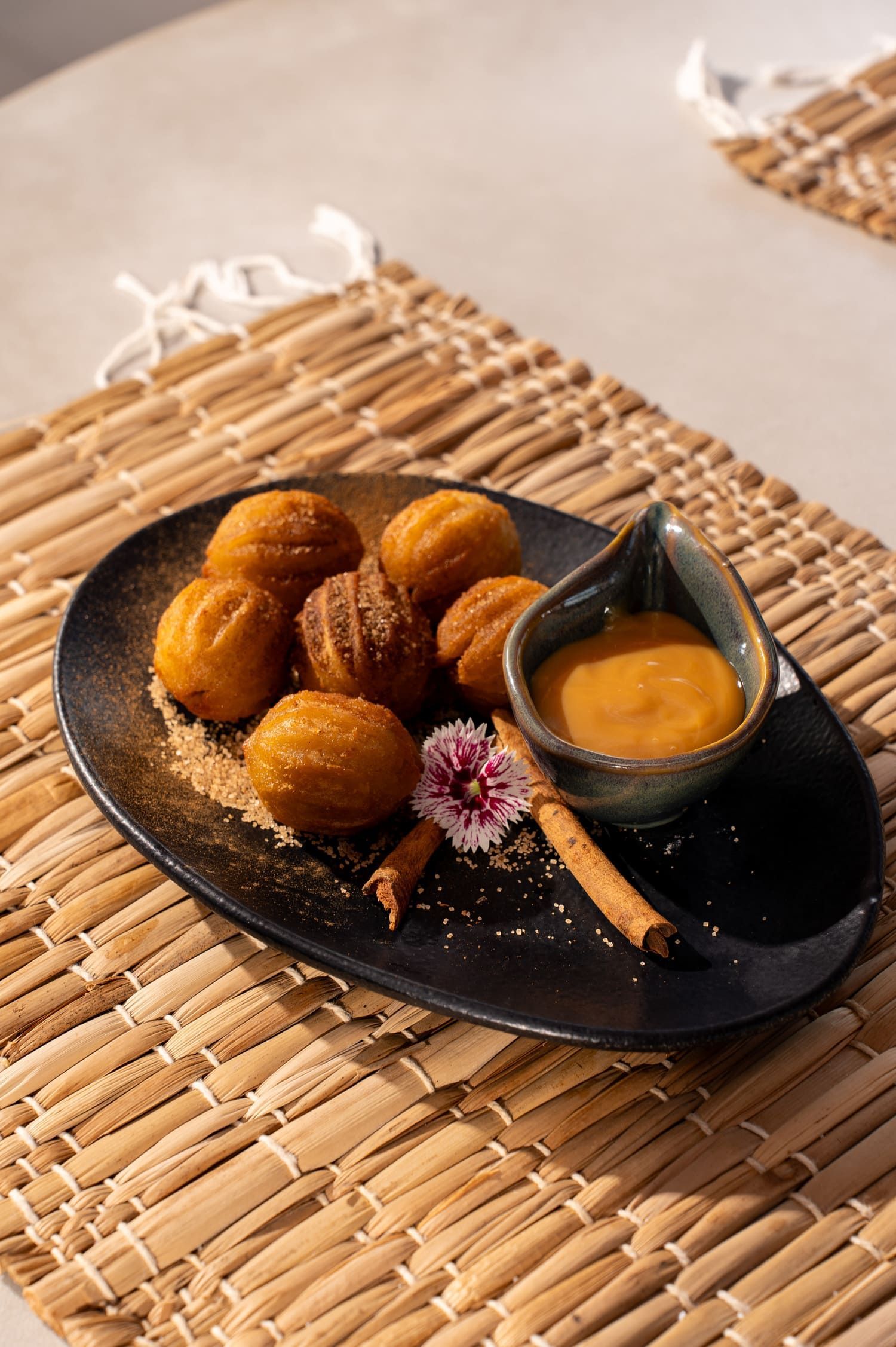 Um prato de comida com uma tigela de molho sobre um jogo americano sobre uma mesa.