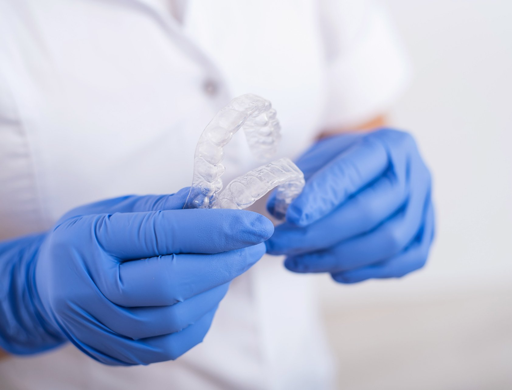 dentist holding molded clear aligners for teeth straightening