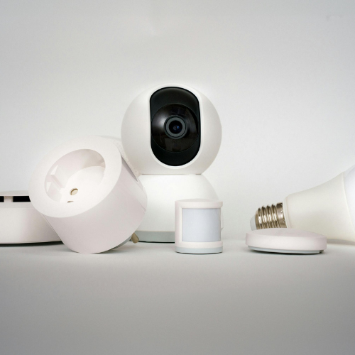 Een camera, een bewegingssensor en een gloeilamp staan op een tafel.