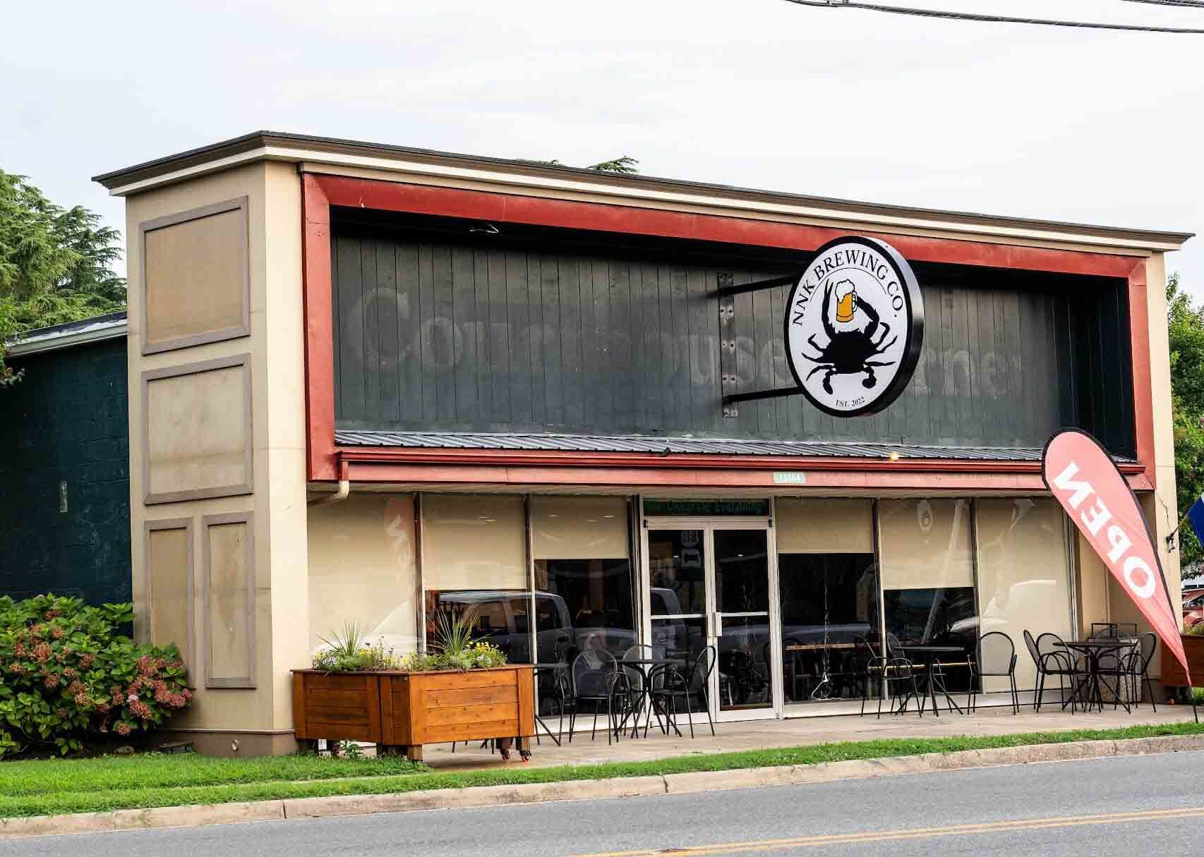 Exterior of a seafood restaurant with a sign depicting a crab. Beige building with a red awning. An "Open" sign is displayed.