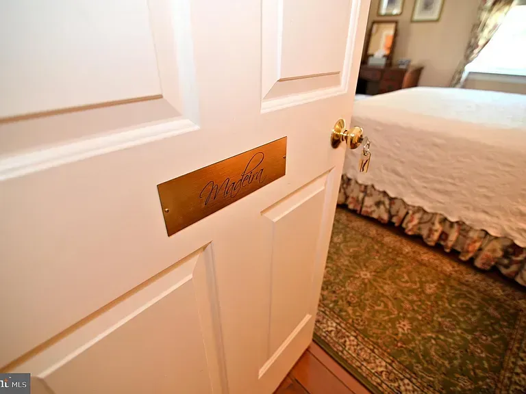 White door with brass nameplate reading "Marbles," open to a bedroom with a bed and green rug.