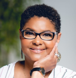 A woman wearing glasses and a watch is smiling for the camera.