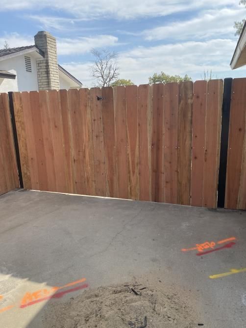 A wooden fence is being built in a driveway next to a house.