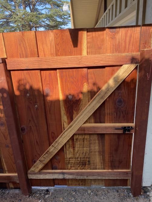 A wooden gate is sitting next to a wooden fence.