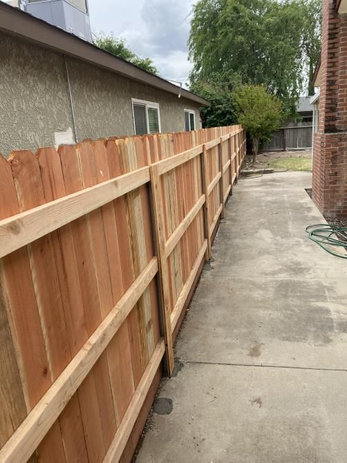 A wooden fence along a sidewalk next to a house.