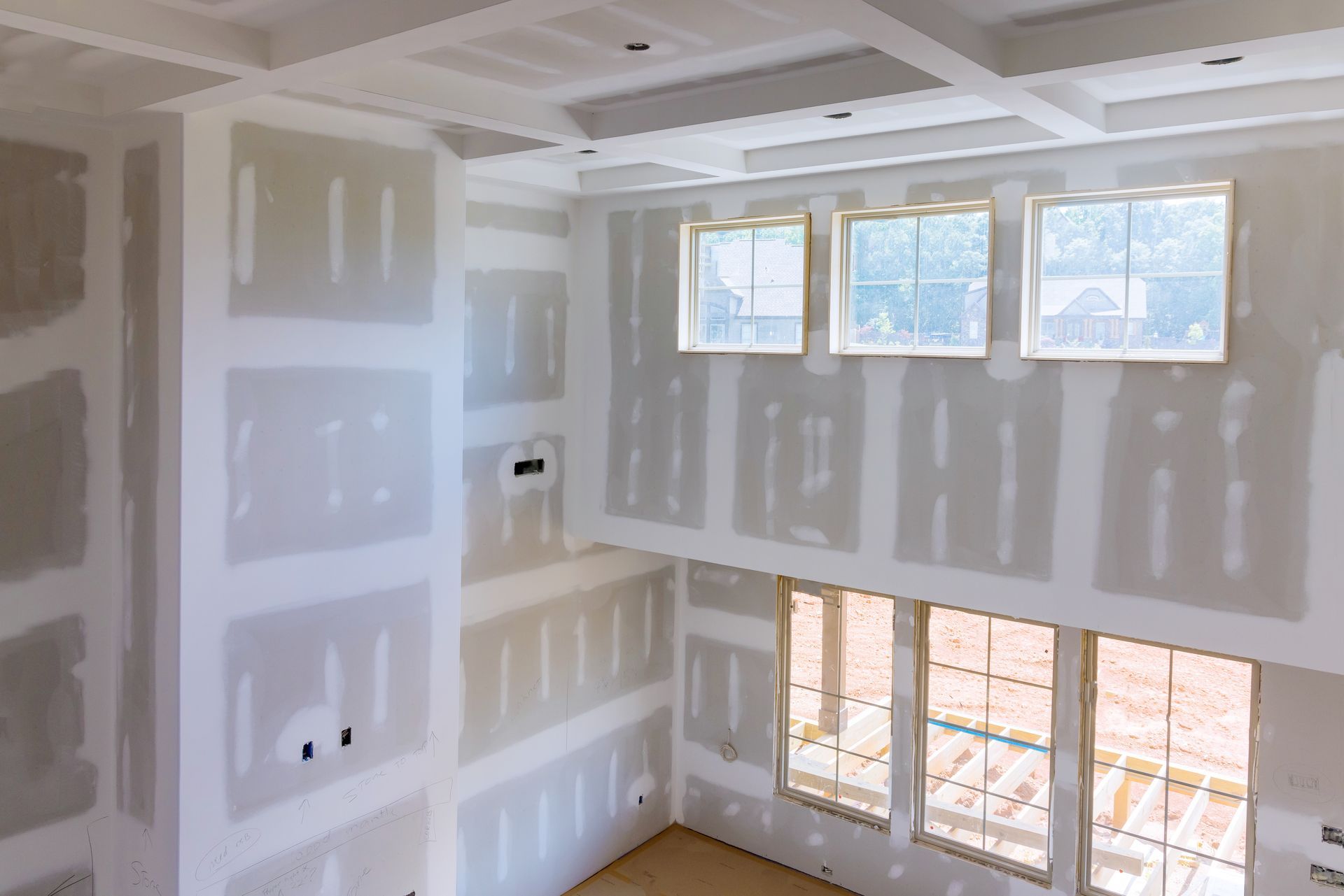 A room with a lot of windows and drywall on the walls.