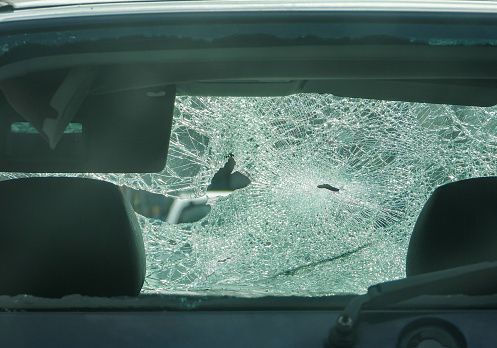 A car with a broken windshield is parked on the side of the road.