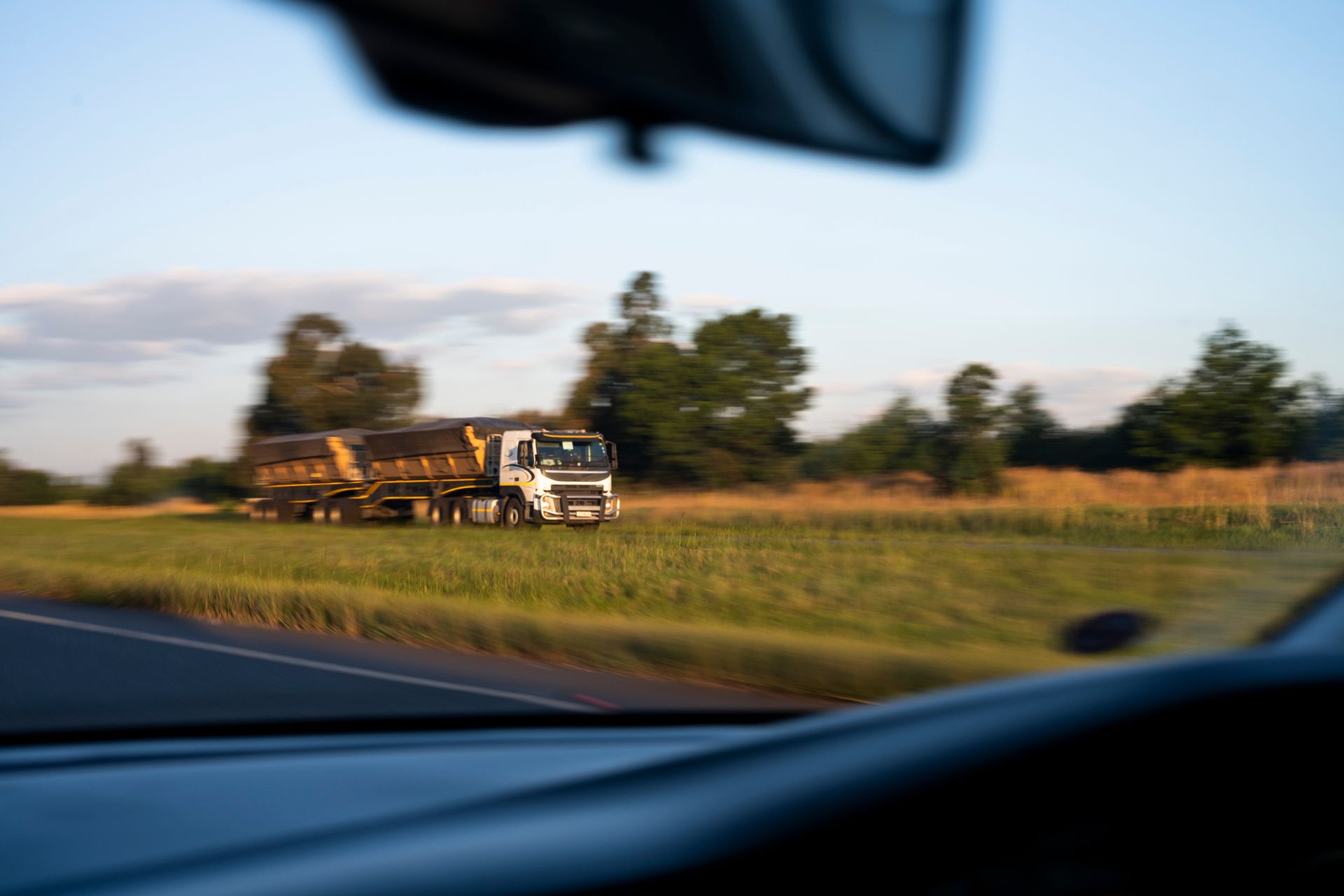 A truck is driving down a road in a field.