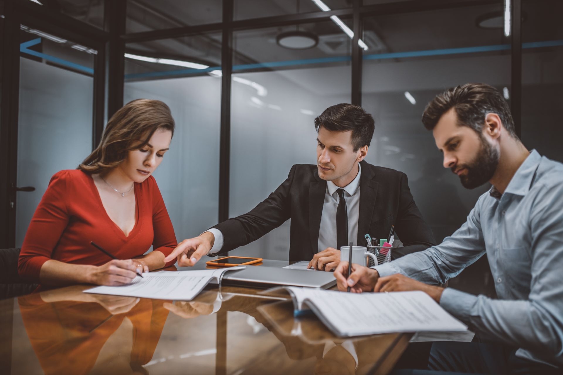 Divorce lawyer guiding clients through paperwork and agreement discussion at office table.