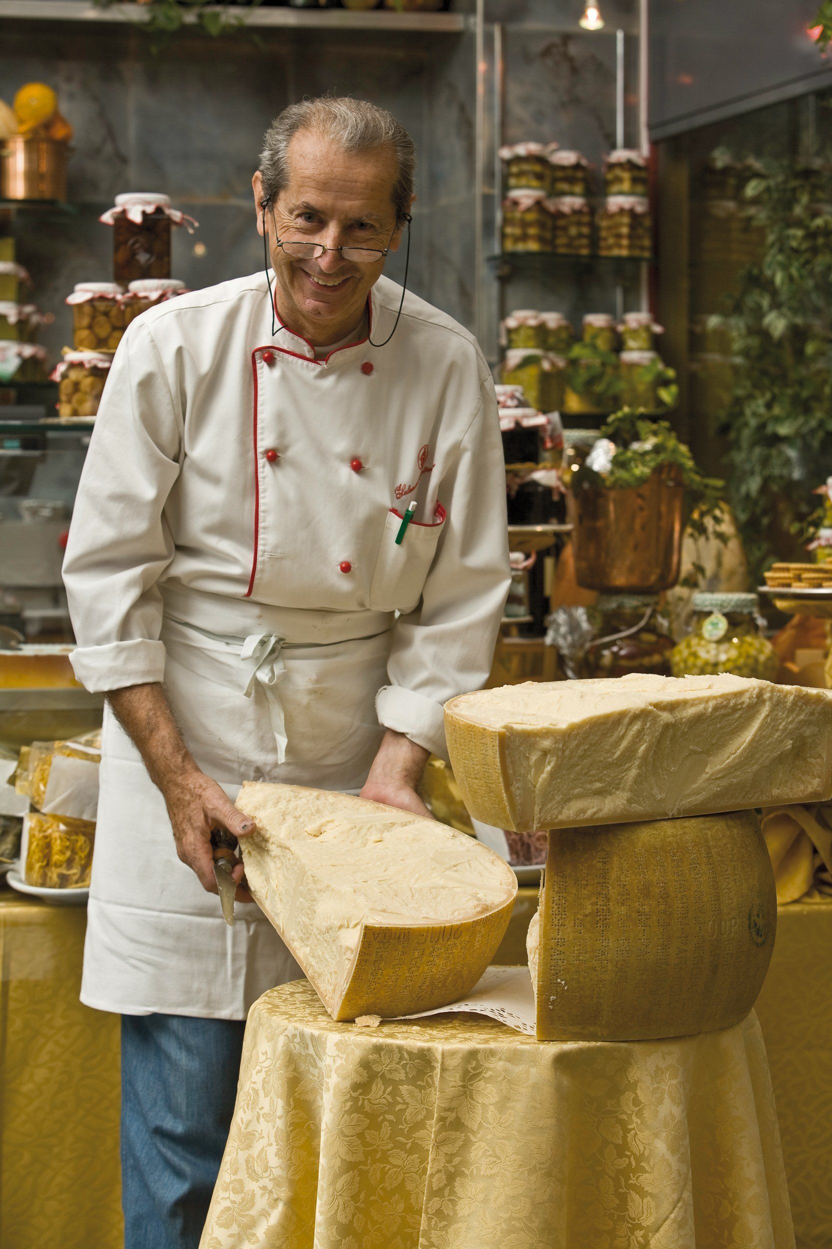 Un uomo in uniforme da cuoco è in piedi accanto a una pila di formaggio.
