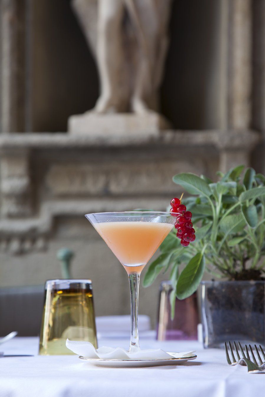Su un tavolo c'è un bicchiere da martini pieno di liquido arancione.